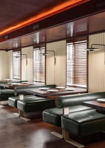 A restaurant interior with multiple dining tables and chairs, inviting atmosphere, and natural light from windows