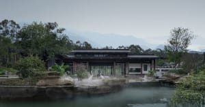Serene Asian-style house near water with multiple rooms, chairs, and potted plants