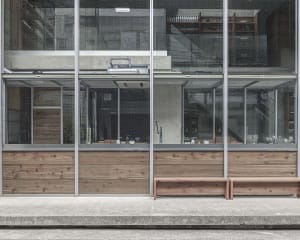 A modern building with a large glass wall and two benches inside, surrounded by natural light