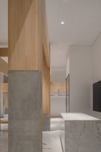 Open modern living space with a marble countertop island, wooden beams, and a TV mounted on the wall, accompanied by two couches and a dining table