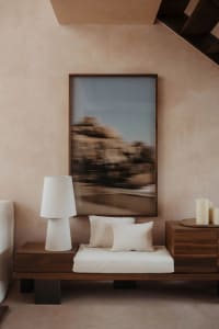 Cozy bedroom with a large mirror above a bench, pillows, and two lamps creating a warm and inviting atmosphere