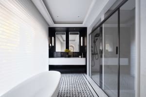 Modern bathroom with a white tub, black accents, two sinks, and a glass shower door, set in a clean and well-lit space