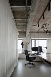 Office space with a desk area, two chairs, a TV screen, and a window view allowing natural light to enter the space