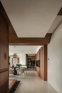 A modern kitchen and dining area with wooden floors and walls, featuring a dining table and chairs, and a kitchen with a refrigerator and oven