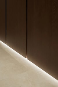 A room with a brown wooden wall, two doors, and a light shining through one of them, creating an interesting effect