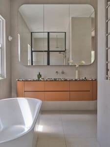 Bathroom with a bathtub and sink, decorated with vases and a mirror, in a clean and organized space