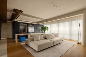 Open living area with a couch, chairs, dining table, and a potted plant, featuring a flat screen TV and natural light