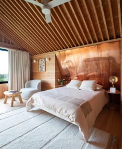 Cozy bedroom with a large bed, two chairs, and a dining table, featuring white bedding and a warm atmosphere