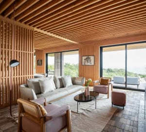 Open living and dining area with wooden floors and walls, featuring multiple seating options and a dining table