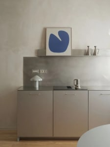 A clean and organized kitchen with a sink, refrigerator, and countertop, featuring two bottles and three cups arranged in a neat and tidy space