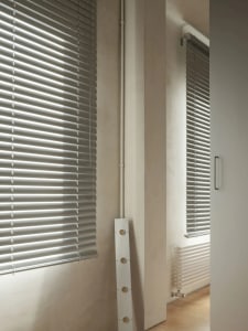 Interior room with white blinds, natural light, and a wall-mounted air conditioner unit