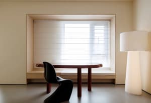 Dining area with a wooden table and two chairs, natural light from a window creates a bright atmosphere
