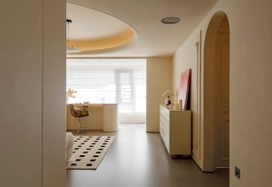 Open modern living area with a kitchen, dining table, and living room featuring white cabinets, clean lines, and neutral tones