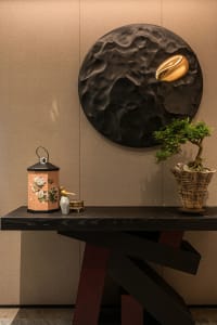 A wooden table in a cozy home office setting with vases, bottles, and a potted plant, creating a warm and inviting atmosphere