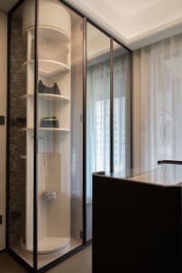 Modern living space with a glass door leading to an open balcony, featuring handbags and a clock on the walls, with a clean and organized atmosphere