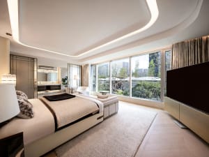 A comfortable living room with a white bed, black headboard, and natural light from windows, surrounded by couches and a TV