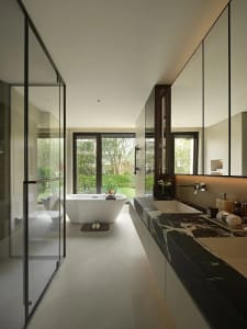 Modern bathroom with a white bathtub, two sinks, and a window allowing natural light to enter the space