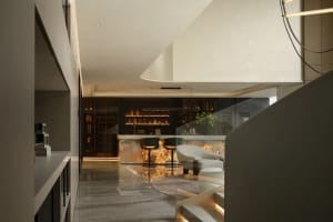 Open concept living area with white walls and floors, featuring chairs, a dining table, and a potted plant, with a bright and inviting atmosphere