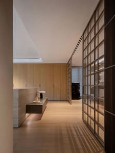 Modern kitchen with wooden floors, two sinks, a refrigerator, and a dining table, featuring clean lines and minimalistic design elements