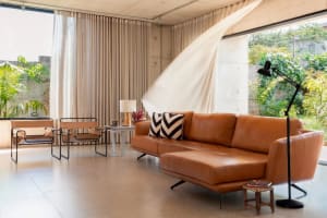 Comfortable living room with a large couch and two chairs in a modern space with white walls and brown leather furniture
