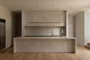 Modern kitchen with a marble countertop island featuring two sinks and a refrigerator, set against a clean and minimalist backdrop