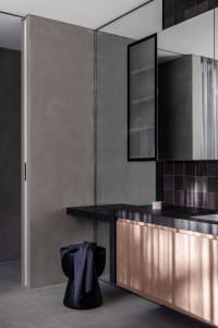 Modern bathroom with two sinks, marble countertop, and a cabinet with books above it