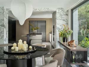 A modern kitchen and dining area with a black table, chairs, potted plants, and appliances