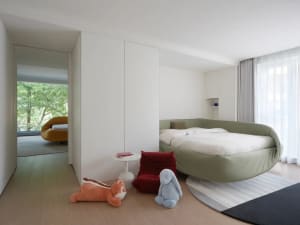 Cozy bedroom with a large bed, white headboard and footboard, a stuffed animal, and a chair in a well-lit space