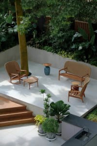 Well-lit outdoor patio with two wooden chairs and two benches on a concrete surface, inviting atmosphere