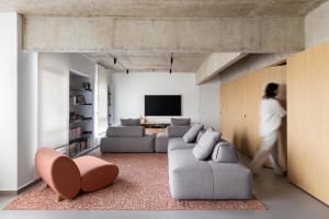 Modern living area with concrete walls and flooring, leather furniture, and dim lighting, creating a cozy atmosphere