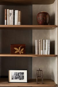 A wooden bookshelf filled with various books of different sizes, arranged in an organized manner, creating a cozy and intellectual environment