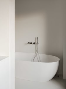 A modern bathroom with a round tub, white walls, and two faucets, giving a clean and bright appearance