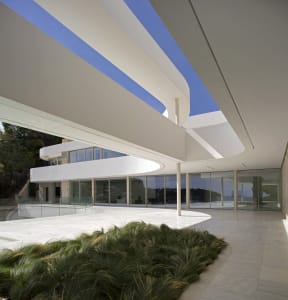 A modern building with a curved structure and a large glass wall that allows natural light to enter the interior spaces, creating a bright and airy atmosphere