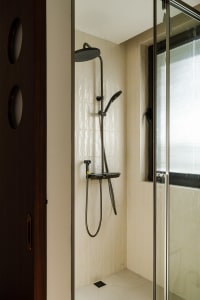 Bathroom with a tile shower, black shower head, and silver pole, featuring natural light from a window