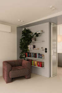 A cozy reading nook with a chair, bookshelves, and a doorway, featuring a warm and inviting atmosphere with books and comfortable seating