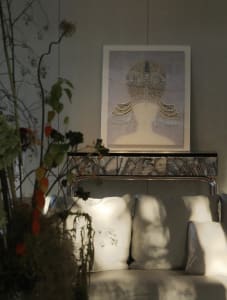 A sophisticated living area with a white couch, a chair, and a painting on display, set against a stone wall
