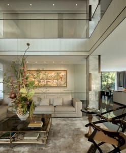 A modern living room with white walls and floors, featuring two couches, a chair, and a vase, with a well-lit and inviting atmosphere