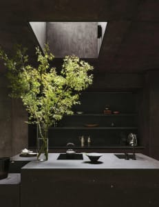 A kitchen scene with a sink, countertop, and various items arranged on the counter, creating a cozy and functional atmosphere