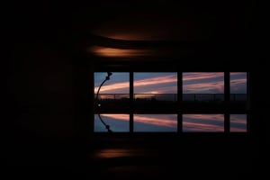 Dimly lit interior space with a large window reflecting the sky, creating a sense of depth