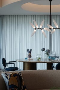 Dining area with a round table, chairs, a vase, and a teddy bear, set in a sophisticated and playful atmosphere
