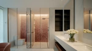 Modern bathroom with a pink tiled wall, two sinks, and a glass shower stall with a clear door