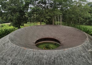 A serene interior space with a circular room featuring a stone-like appearance, potted plants, and a calm atmosphere