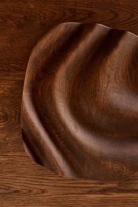 A wooden bowl sits on a wooden table in a cozy and inviting space with a warm and natural ambiance
