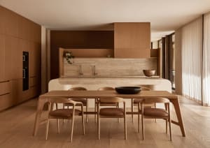 A modern kitchen with wooden floors and cabinets, featuring two dining tables and chairs, creating a clean and inviting atmosphere
