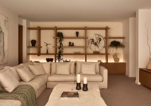 A well-lit living room with two couches, chairs, a dining table, and decorative elements such as potted plants, vases, and books, creating a cozy atmosphere