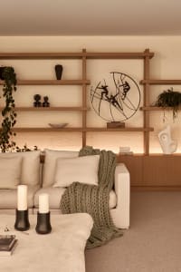 Cozy living room with wooden floors and walls, featuring a dining table, multiple chairs, and couches, with books and potted plants adding to the warm ambiance