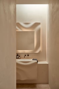 Bathroom with white walls, sink, mirror, and countertop, featuring a bottle on the counter