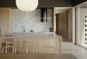 Open kitchen with wooden floors and countertops, featuring a sink, dining table, and two chairs, with a clean and well-organized atmosphere