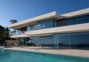 Open living area with glass windows, white walls, and floors, featuring two people in a bright and inviting space