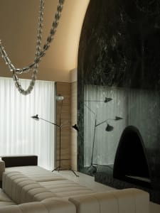Cozy living area with a couch, chair, and fireplace, surrounded by marble walls and lit by two lamps